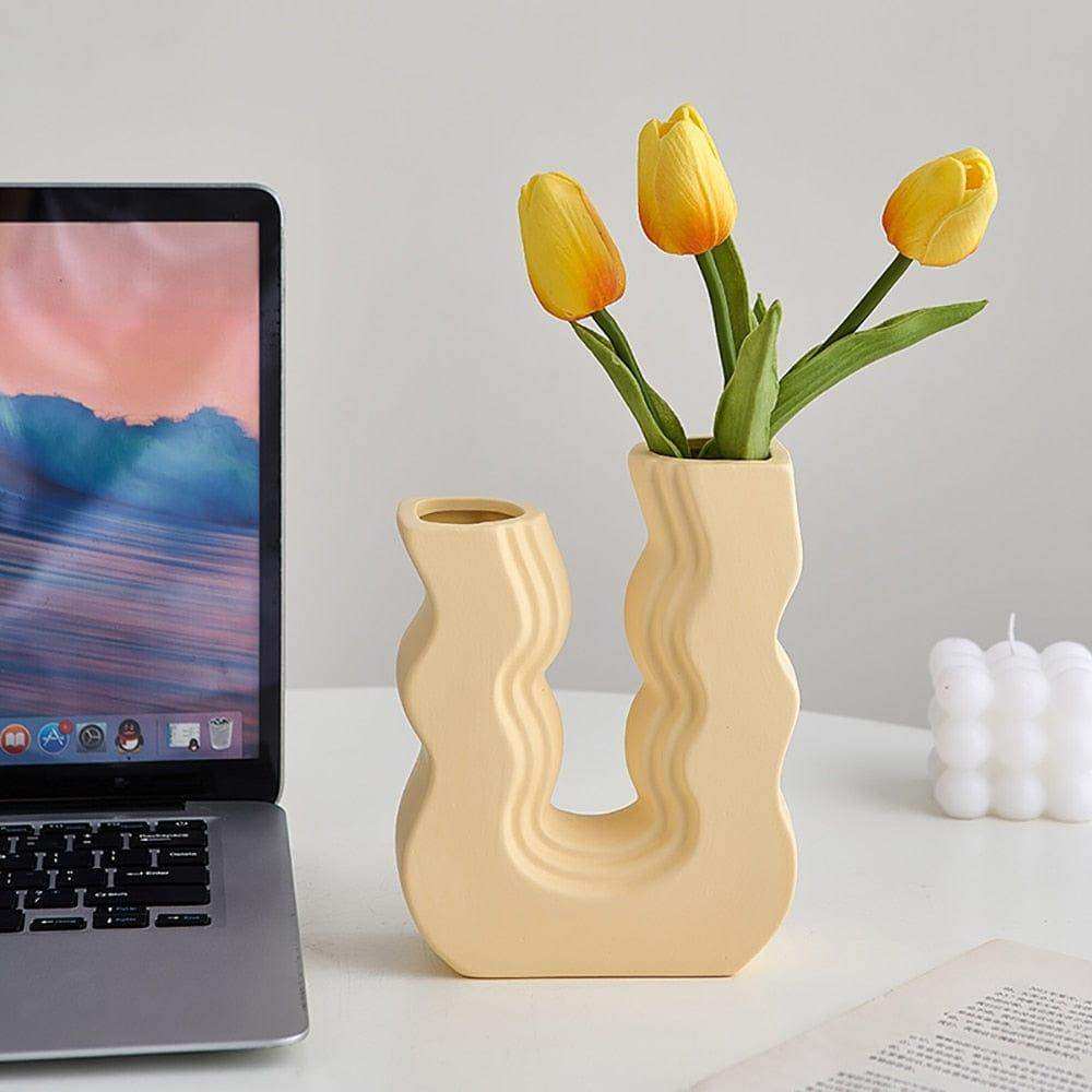 Cream-colored ceramic wavy wonder vase with a modern design holding bright yellow tulips
