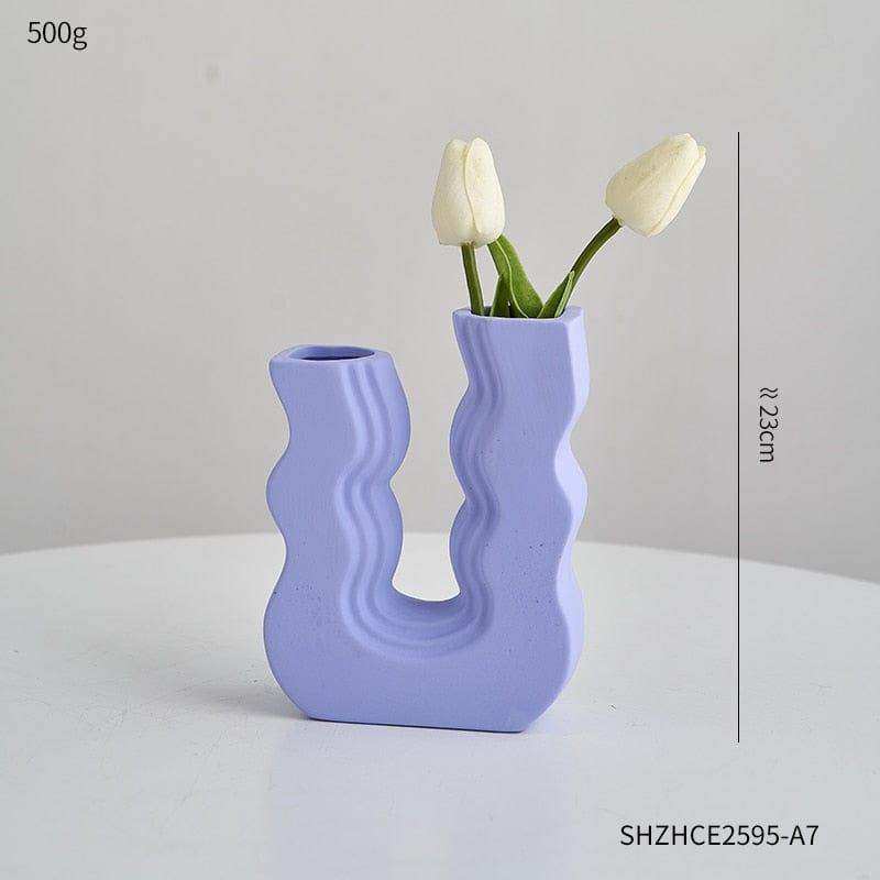 A lavender ceramic wavy wonder vase with a u shaped design holding two white tulips