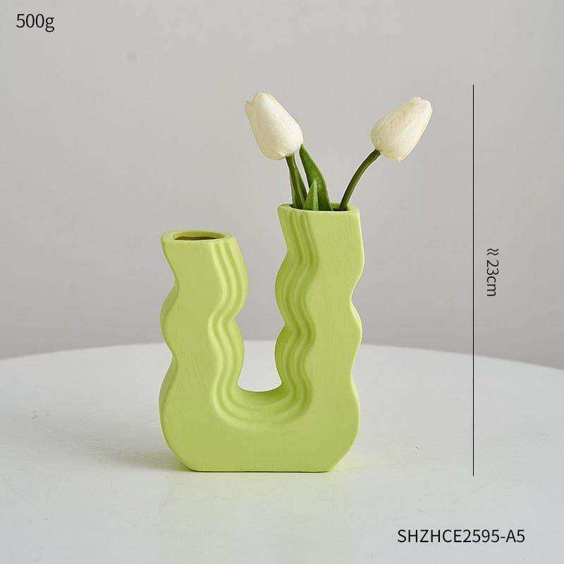 A lime green ceramic wavy wonder vase with a u shaped design holding two white tulips