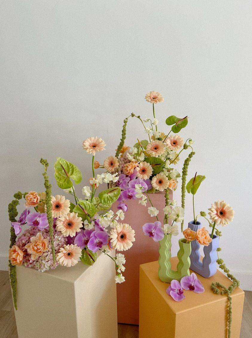 Pastel-colored ceramic wavy wonder vases with modern designs holding peach purple and white flower arrangements
