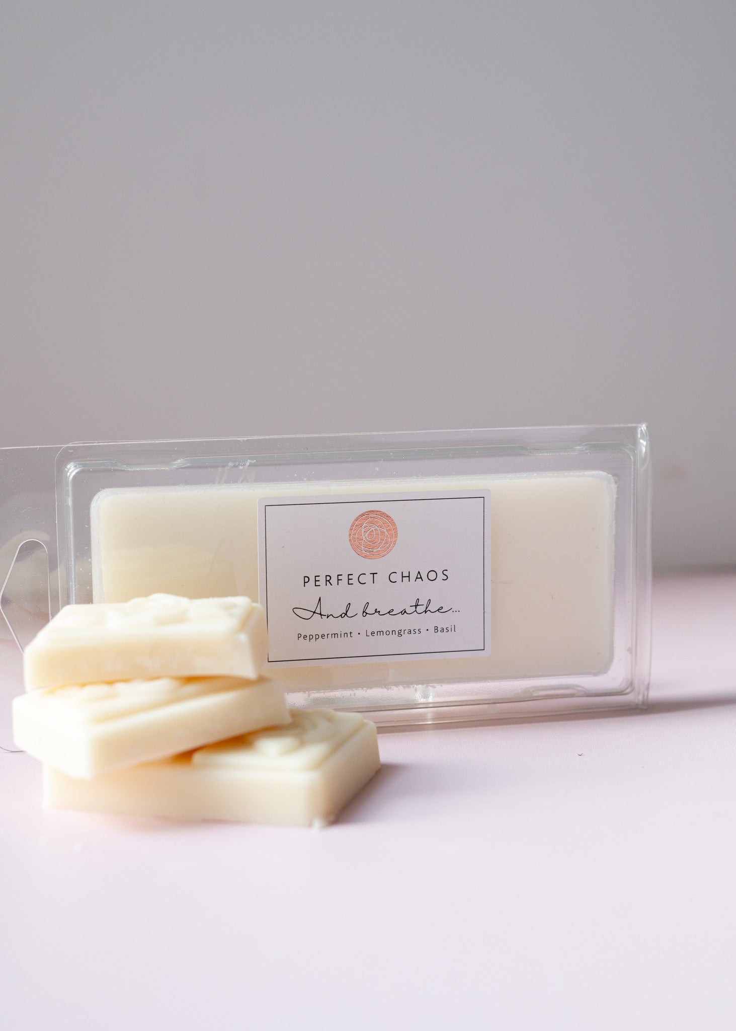 Off-white rectangular wax melts with peppermint lemongrass and basil essential oils in clear plastic container perfect chaos and breathe
