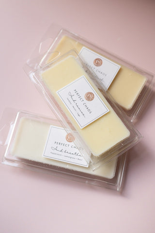 Pale yellow wax melts in clear plastic packaging with perfect chaos label made with essential oils