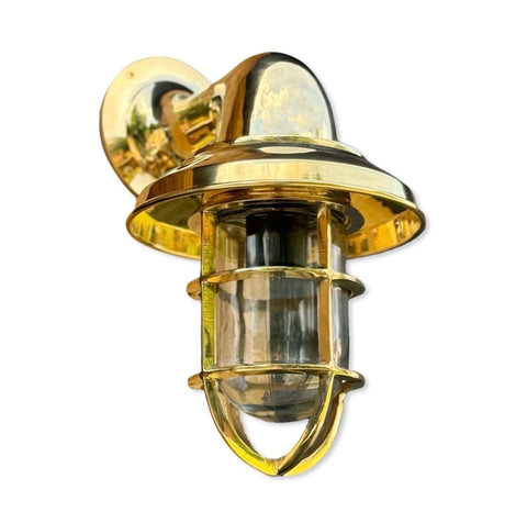 Brass nautical-style wall light with clear glass enclosure and protective cage perfect as a bathroom wall light