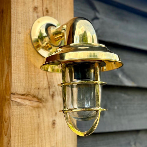 Brass nautical-style solid brass wall light with clear glass and protective cage for bathroom or outdoor use