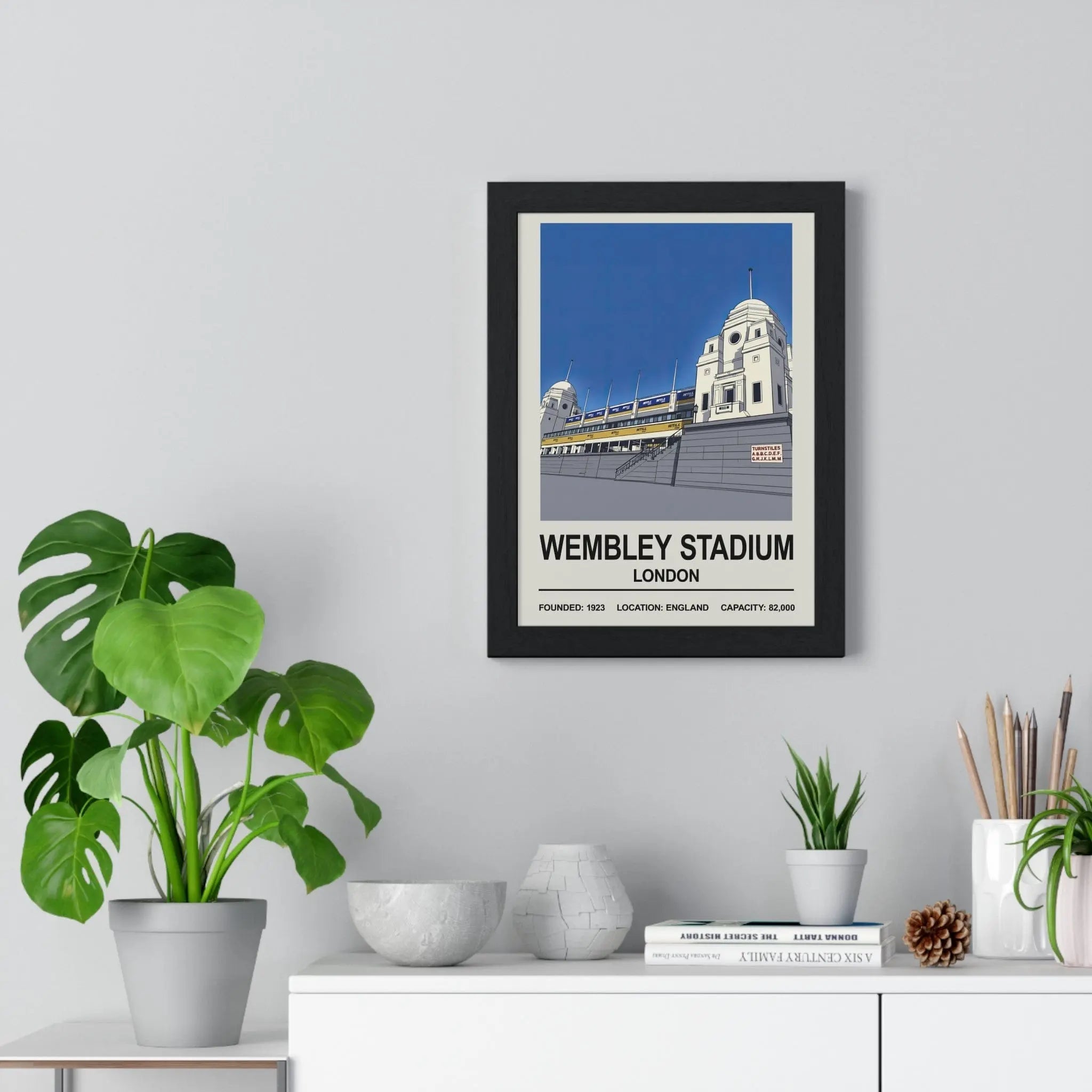 Black-framed wembley stadium print featuring stylized twin towers illustration and bold white text on blue sky background