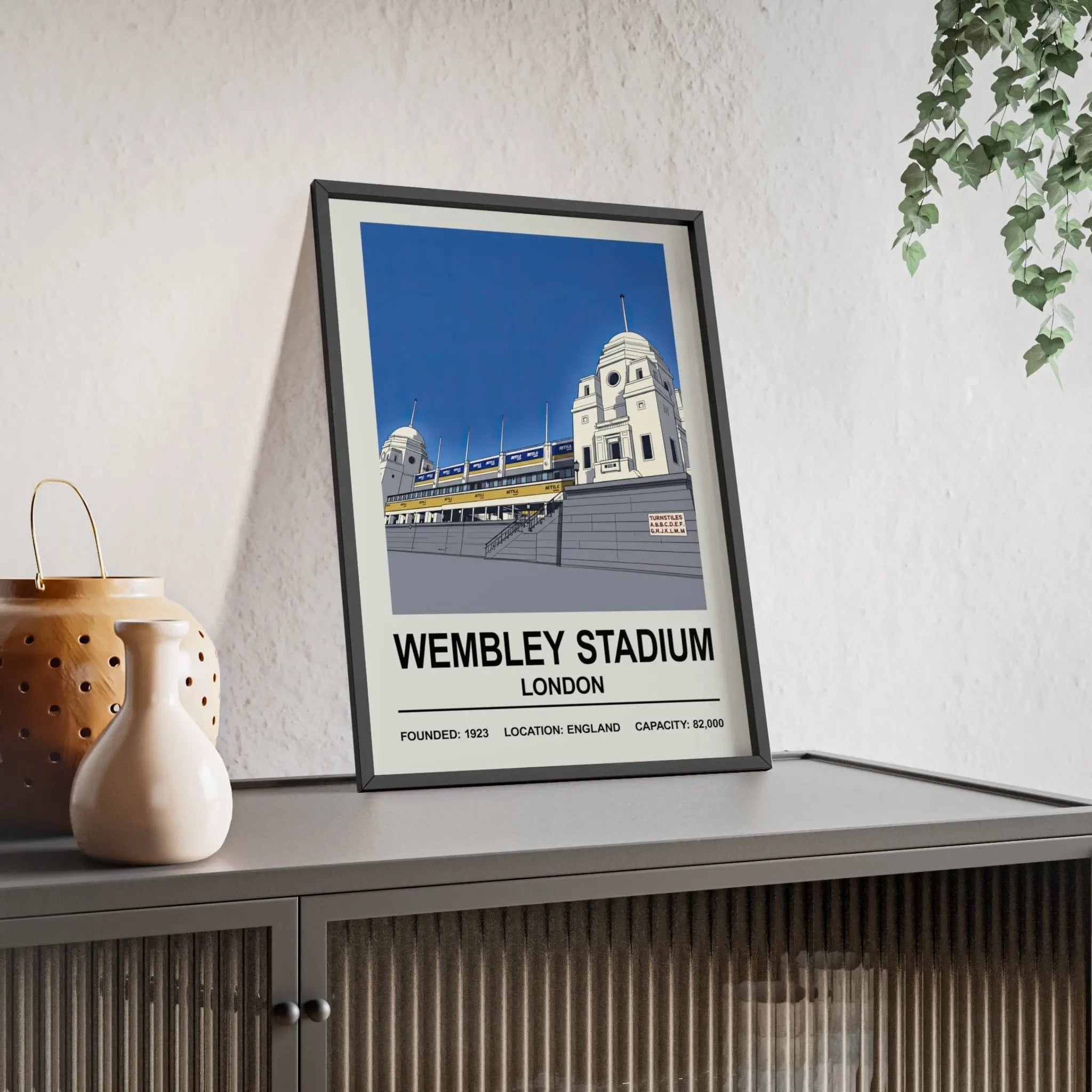 A framed wembley stadium print featuring stylized twin towers with bold blue sky and white architecture