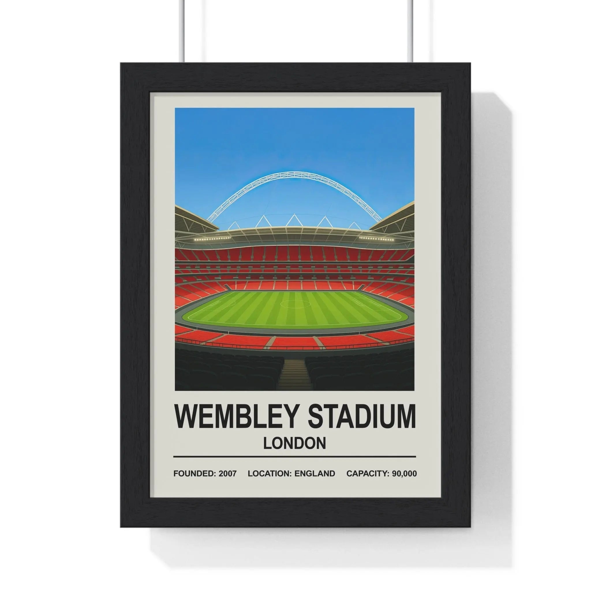 Black-framed wembley stadium poster with stylized green pitch red seating white arch against blue sky background
