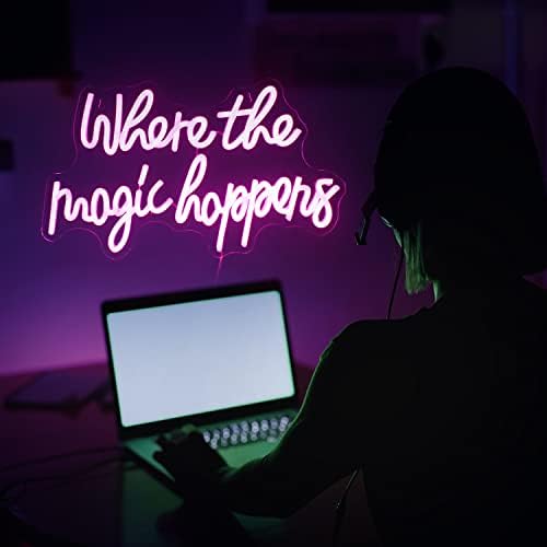 A glowing pink and purple led neon sign saying where the magic happens in cursive for bedroom wedding decor