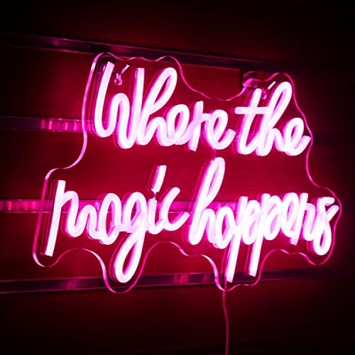 A glowing pink led neon sign with the phrase where the magic happens in cursive for bedroom wedding decor