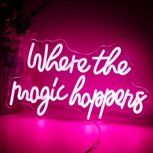 A glowing pink led neon sign with where the magic happens in white cursive for bedroom wedding birthday decor