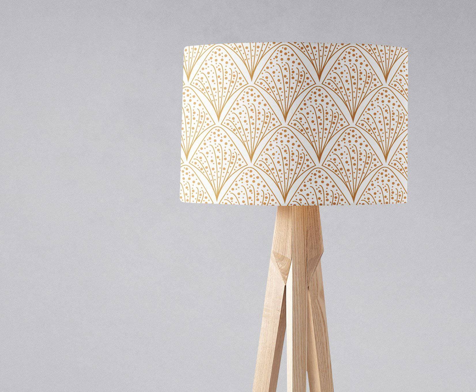 Cream-colored table lamp with gold contemporary art deco pattern on inch diameter light wood tripod base