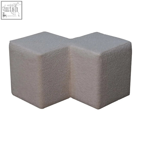 Two interlocking gray concrete pavers on the textured surface of a white boucle twin footstool base