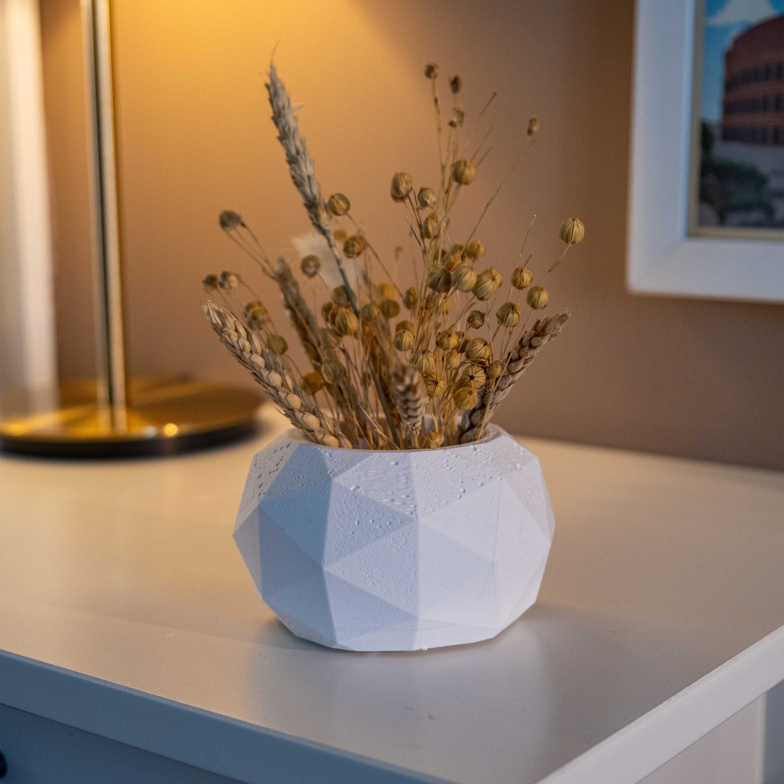 White concrete diagonal pot with a white geometric ceramic vase holding dried golden wheat and seed pods
