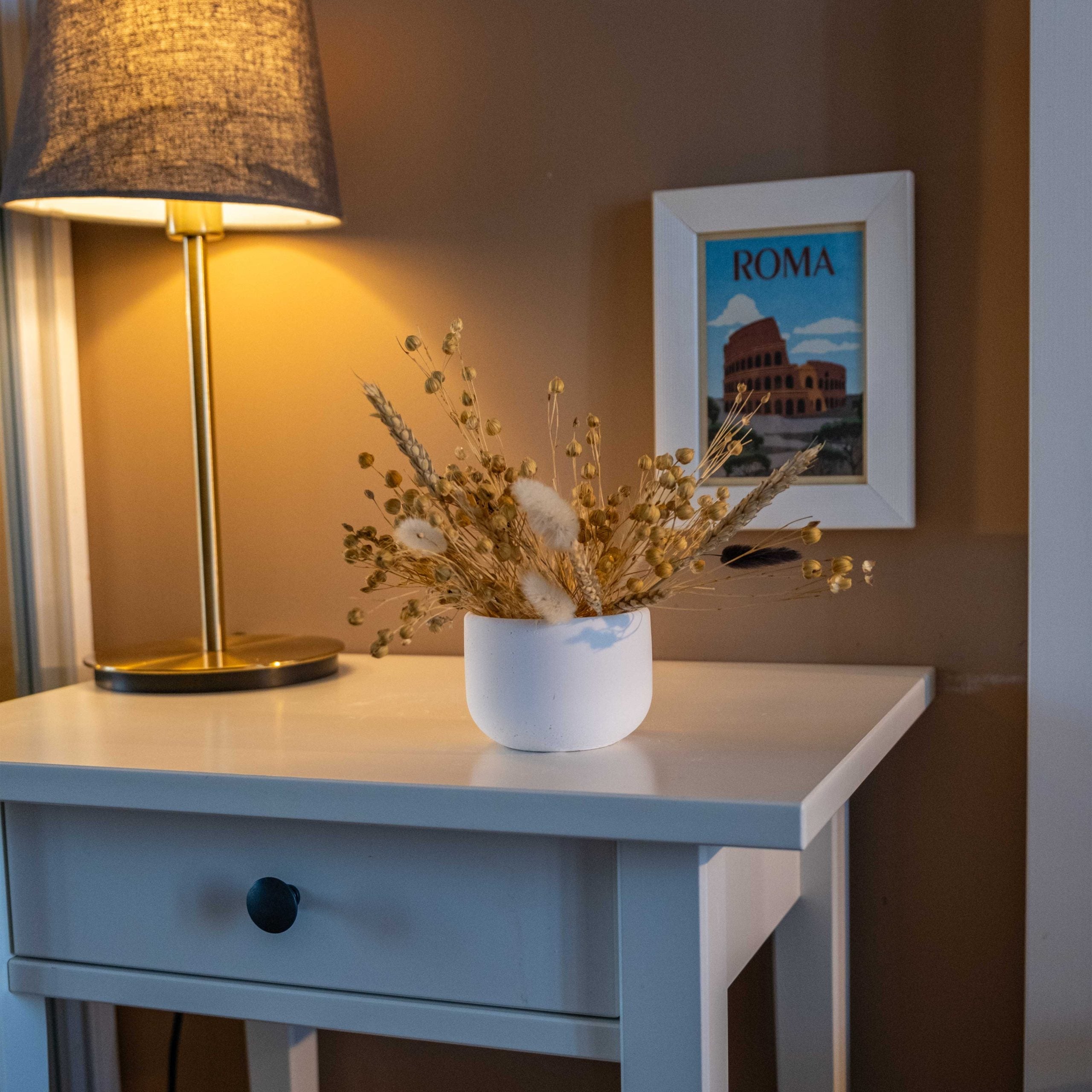 White concrete pine pot featuring a white ceramic vase with dried golden wheat and cotton grass arrangement