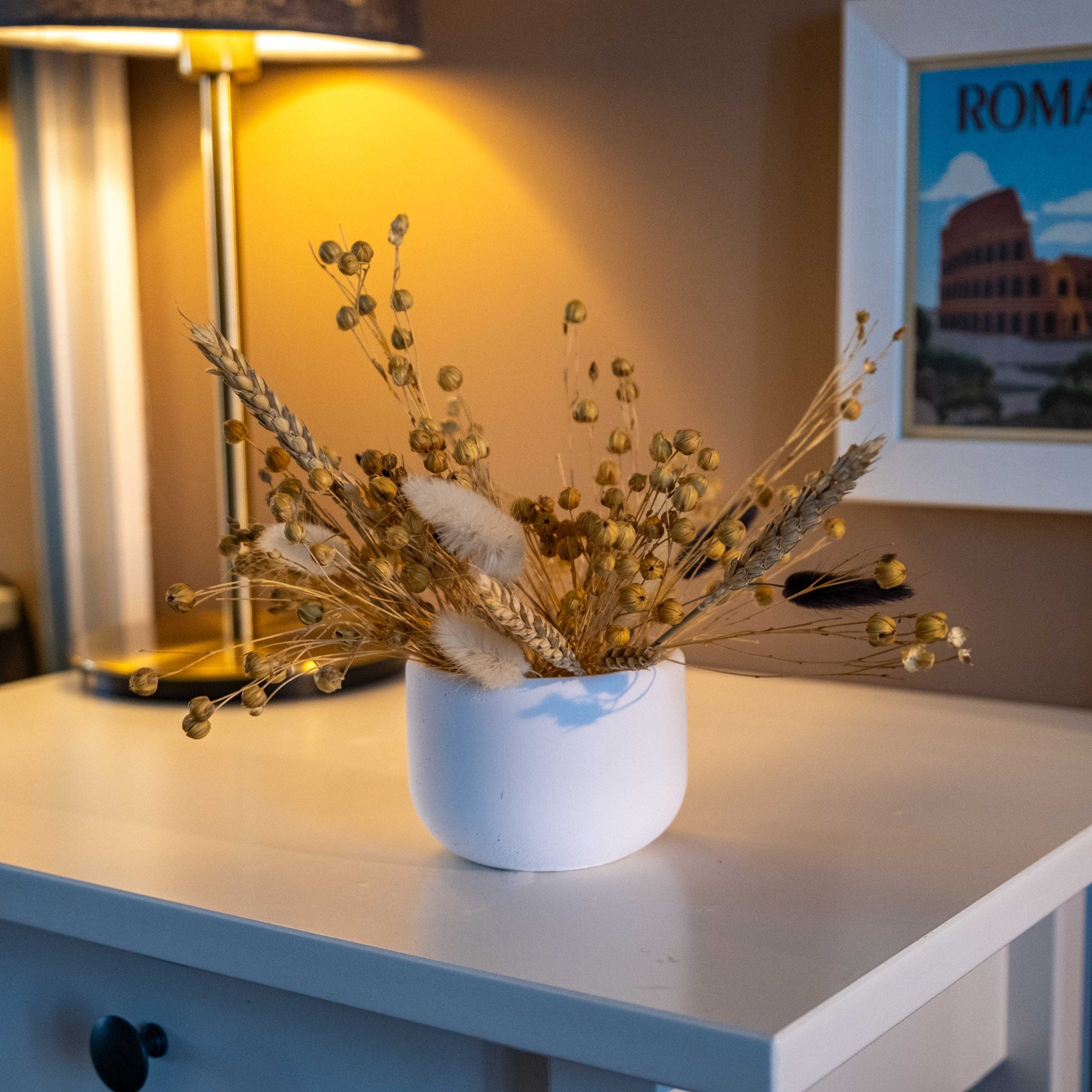 White ceramic vase with dried golden wheat and pampas grass inside a white concrete pine pot for decor