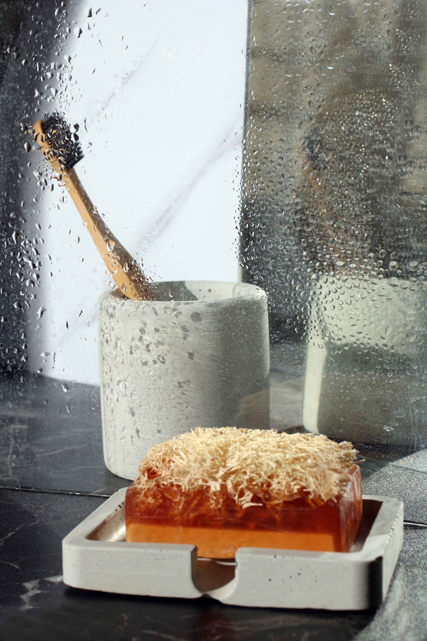 A translucent amber soap bar with textured top in a minimalist white concrete soap holder dish