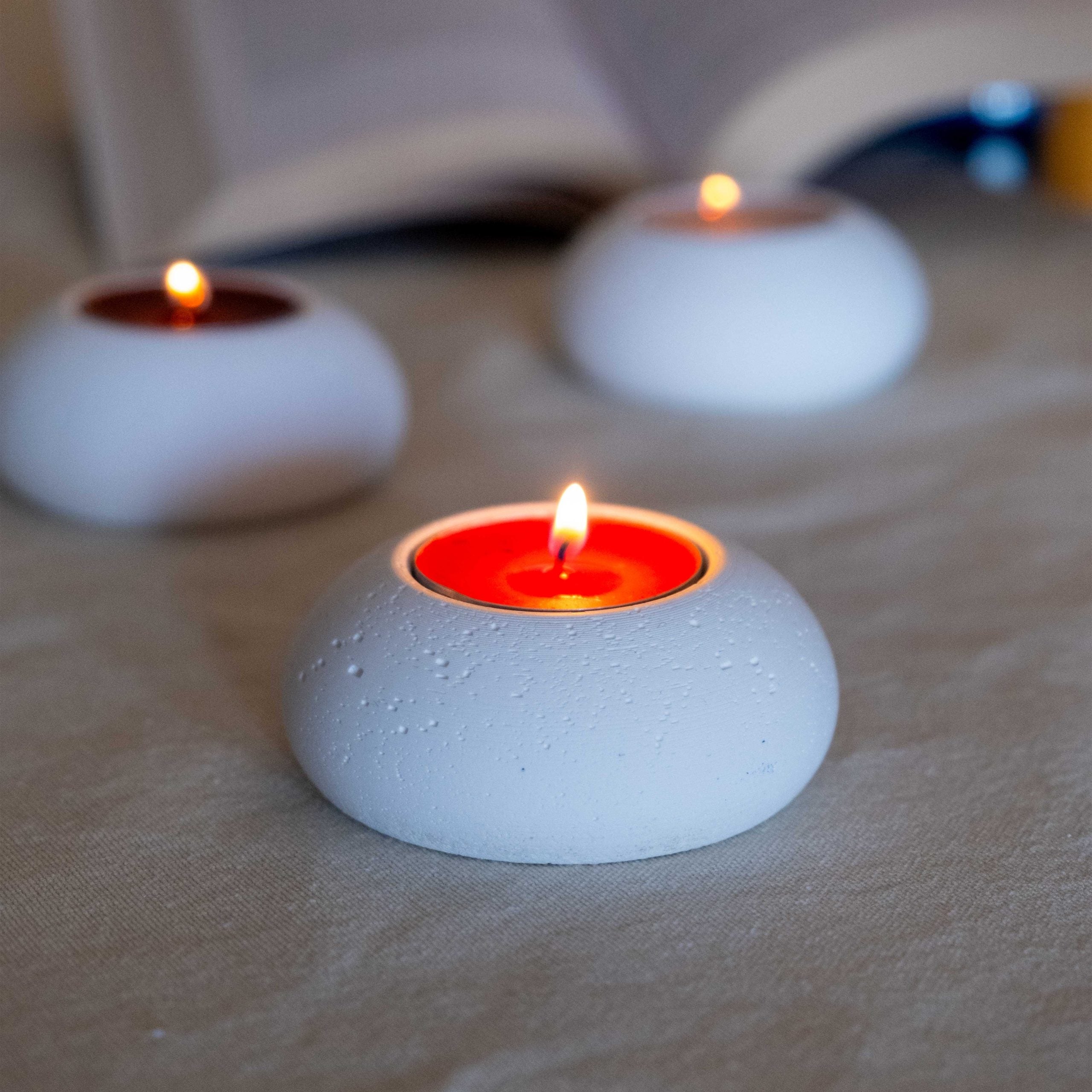 White concrete tealight holder double set with textured ceramic design and glowing red candle inside