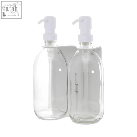 White double wall-mounted soap dispenser with clear glass bottles and white pump tops on a matching holder