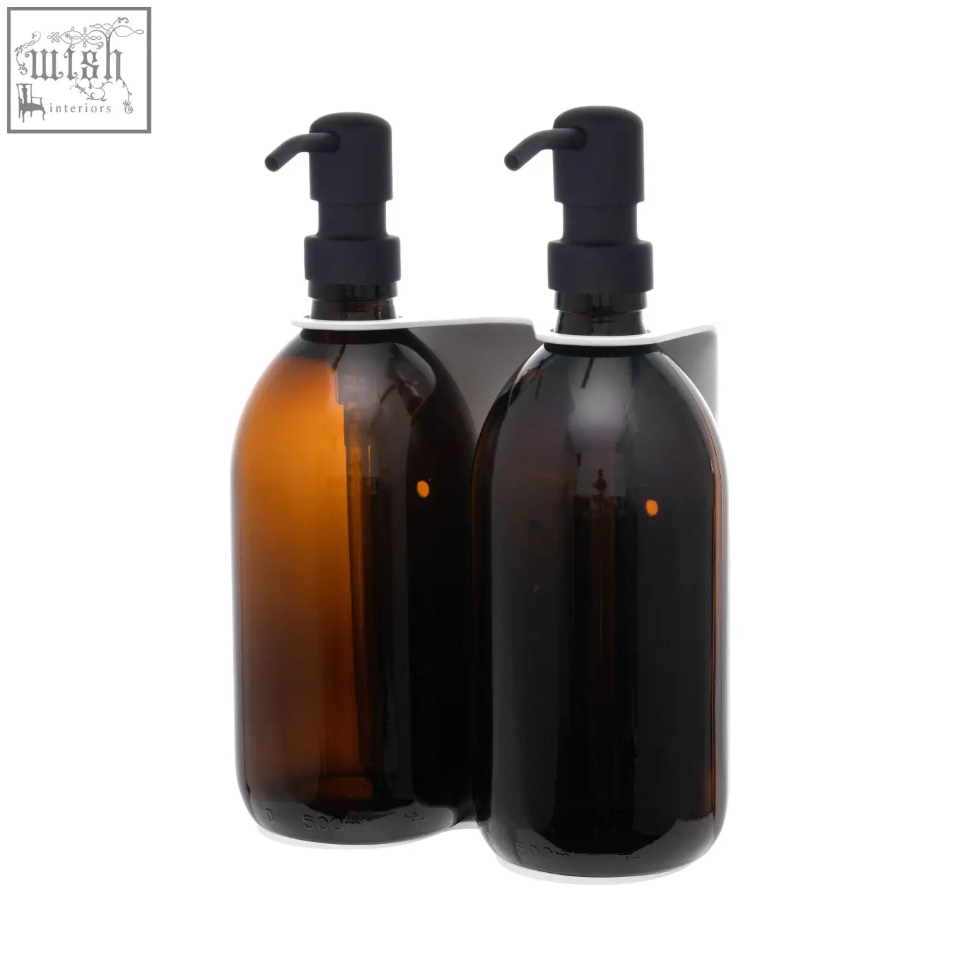 Two amber glass soap dispensers with black pumps in a white wall-mounted soap dispenser bracket