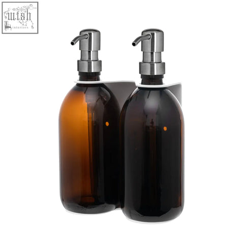 Two amber glass soap dispensers with chrome pumps on a white wall-mounted bracket for easy use and style
