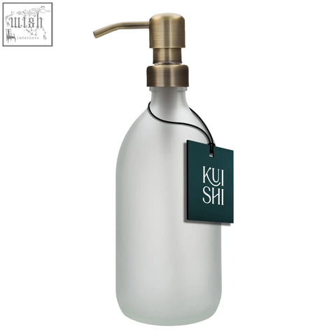 White glass soap dispenser with frosted glass body and brushed brass pump featuring a dark green tag