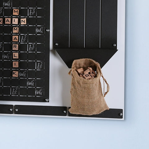 A rustic burlap sack with wooden scrabble tiles for the white words wall game suitable for the player age range