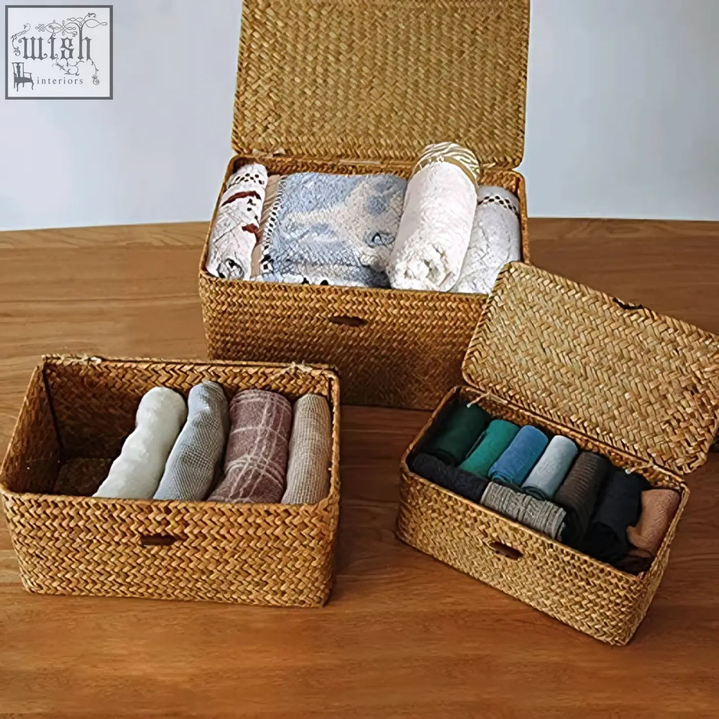 Set of three woven rattan seagrass storage baskets with lids holding folded socks and blankets for living room use