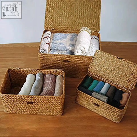 Set of three woven rattan seagrass storage baskets with lids holding folded socks and blankets for living room use