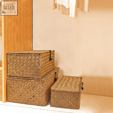 Three woven wicker seagrass storage baskets with black handles stacked by size for bathroom or kitchen use