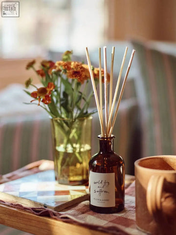 A brown glass wild fig and saffron diffuser by plum and ashby with wooden reeds for consistent fragrance throw using vegetable oil
