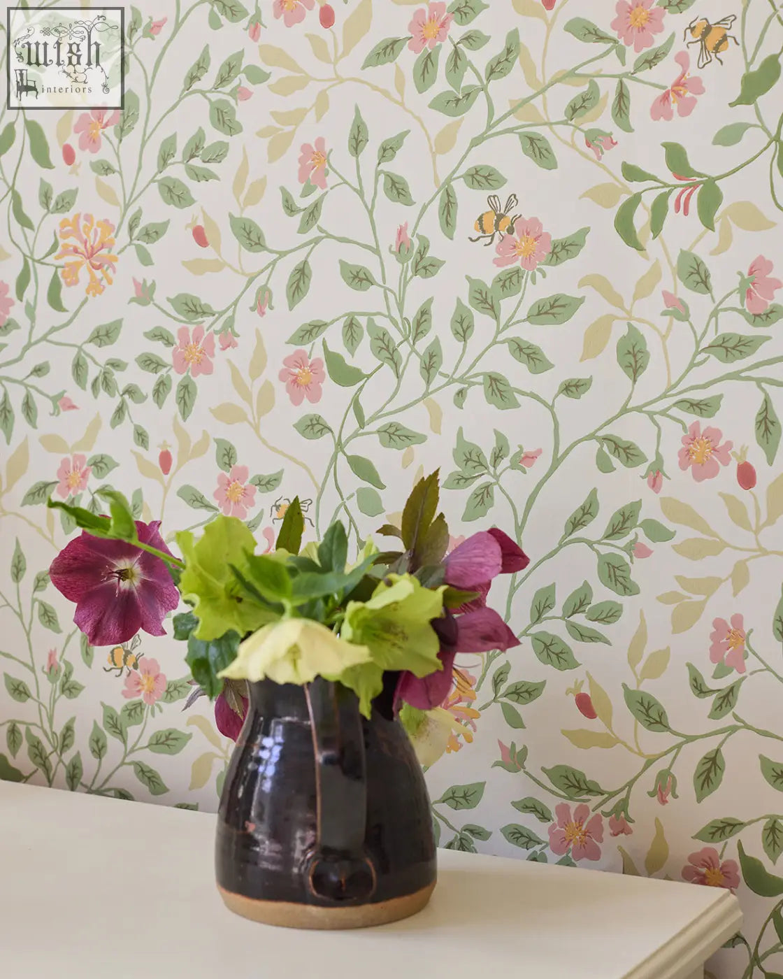 Dark ceramic vase with glossy finish and earthy brown base holding purple and green flowers for wild rose wallpaper peridot