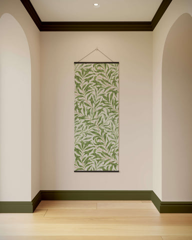 A william morris willow boughs tapestry with a repeating green leaf pattern on light fabric and dark borders hanging vertical