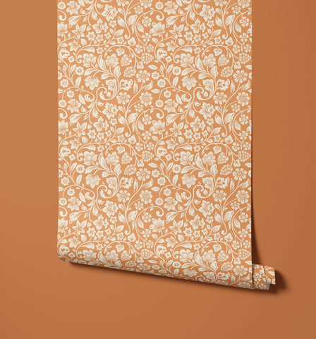 A roll of willow peach wallpaper with an intricate white floral and vine pattern perfect for home decor