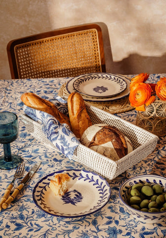 White long rattan basket lined with blue floral cloth holding assorted bread loaves perfect for kitchen storage