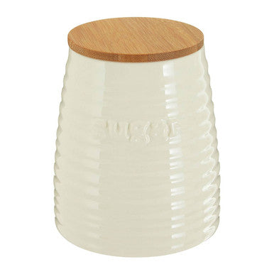 Cream dolomite sugar canister in cream-colored ceramic with vertical ribbed texture and natural wood lid for kitchen storage