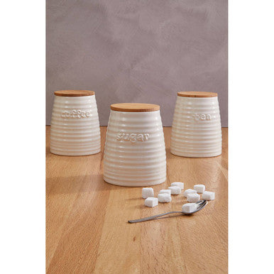 Three white ribbed ceramic cream dolomite sugar canisters with wooden lids labeled coffee sugar and tea
