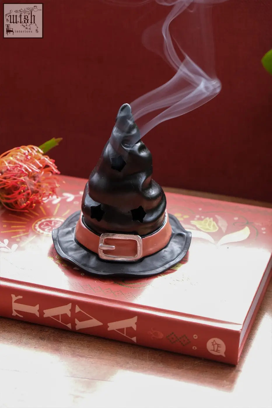 Black witch’s hat incense cone burner with tan belt and silver buckle emitting smoke from the top