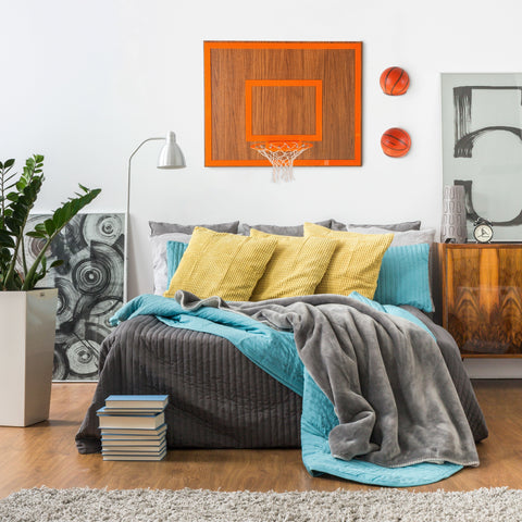 Orange wooden single hoop walnut basketball hoop with net and two orange balls mounted on the wall above bed