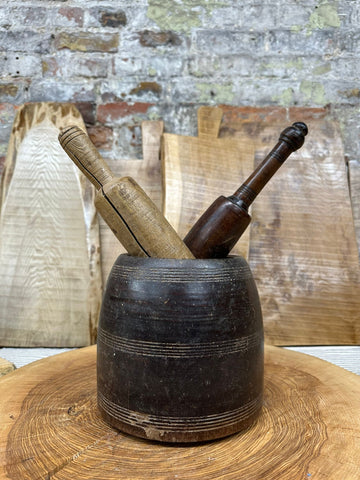 Dark wooden vintage herb plant pot with two wooden pestles in light and dark tones for desk tidy or cutlery holder