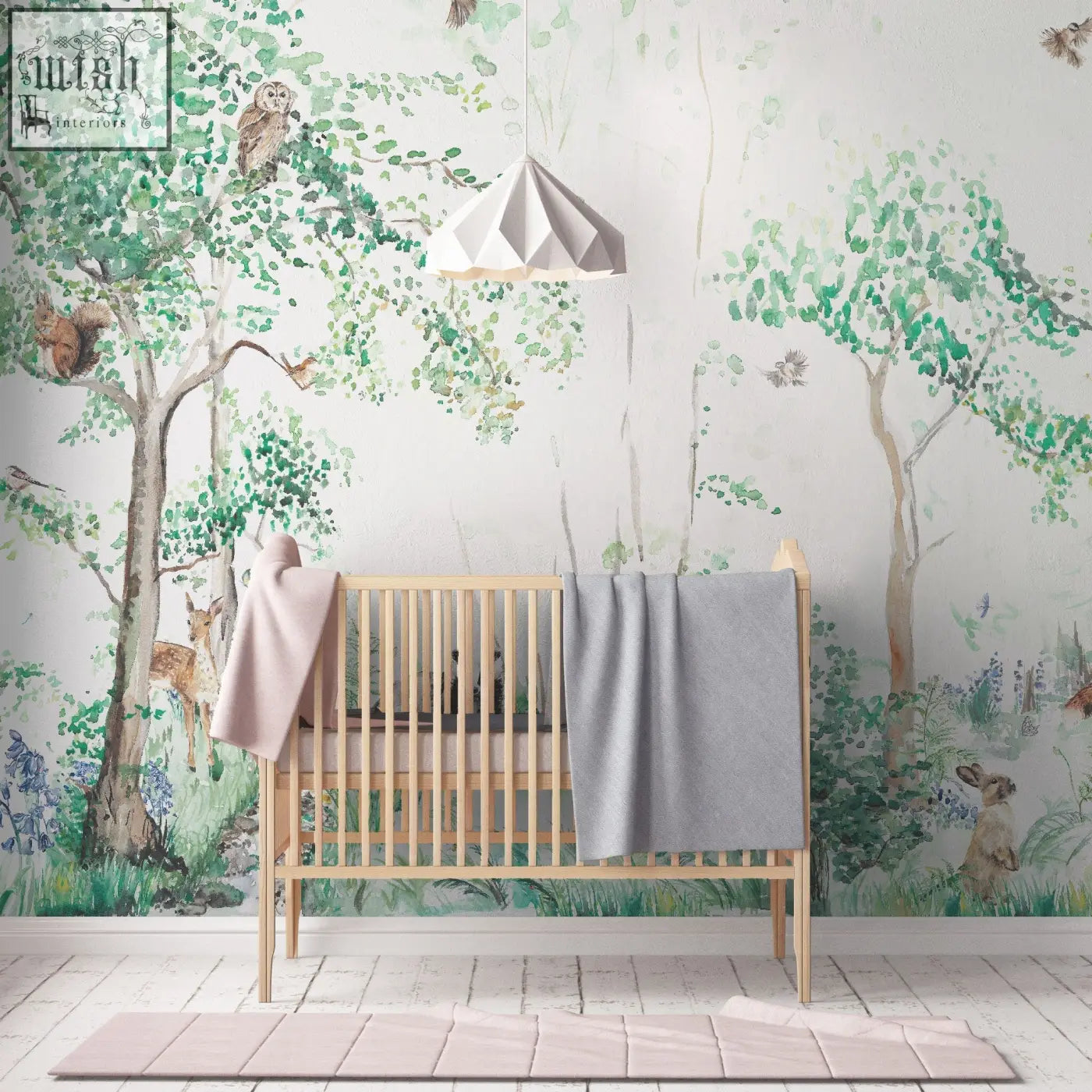 Light wood crib with vertical slats and soft pink and gray blankets in woodland animals children’s mural wallpaper by artist katie 180gsm non-woven