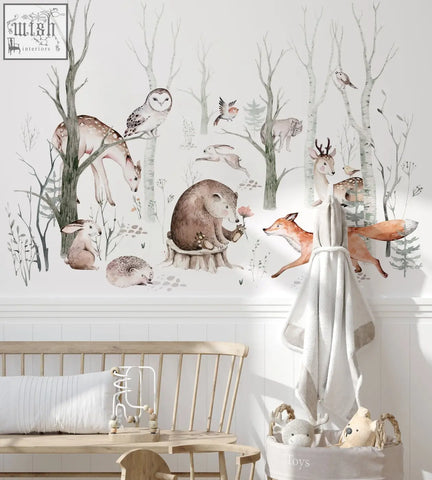 A soft off-white towel with gray trim hanging on a wooden rack near woodland forest wall decals for kids