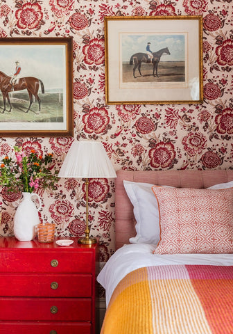 Pink tufted headboard with white pillows and a wool waffle blanket in orange pink check striped quilt on bed