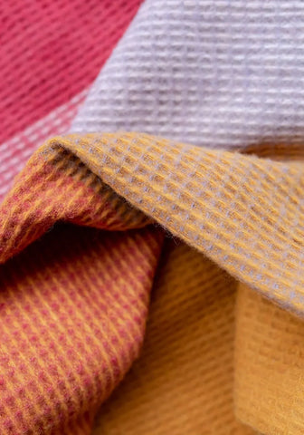 A soft wool waffle blanket in orange pink check with textured knit perfect for cozy warmth