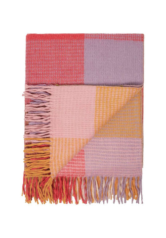 A soft woven wool waffle blanket in orange pink check with colorful patchwork and fringed edges for cozy use
