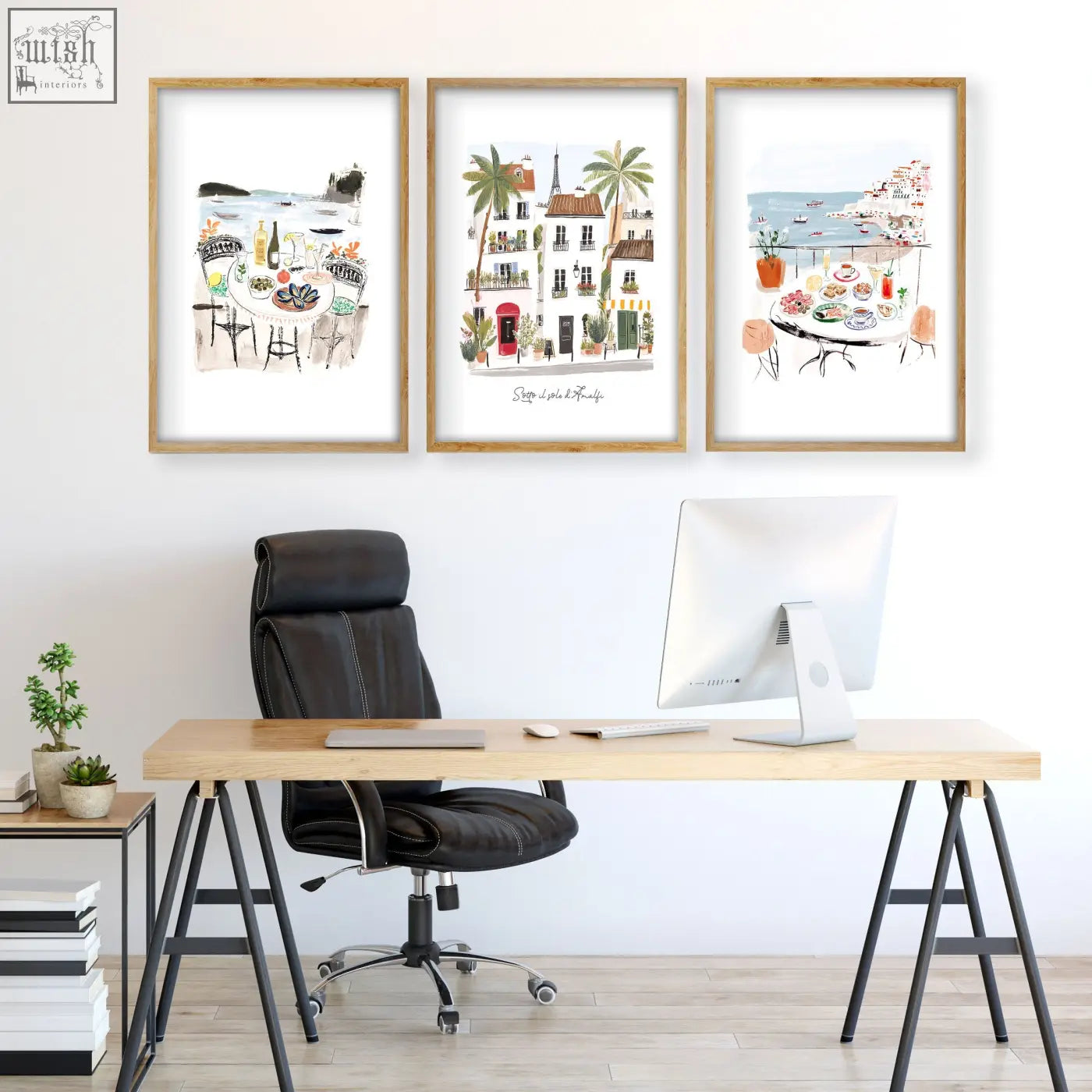 Three framed watercolor prints with light wood frames hang above a wooden desk as office wall art for work office wall