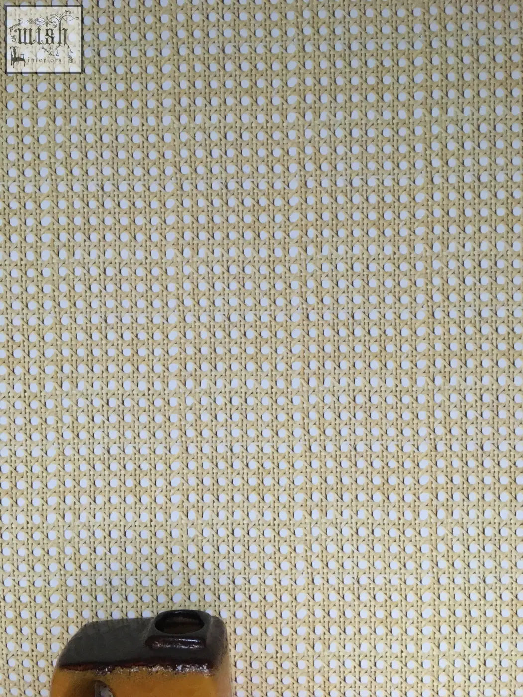 Beige woven cane wallpaper with a mesh texture and small circular holes for a stylish woven cane effect