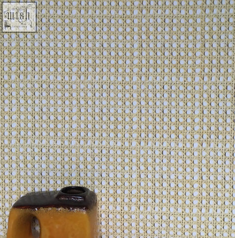 A small mustard yellow ceramic vase with a dark brown rim on a background of woven cane wallpaper texture