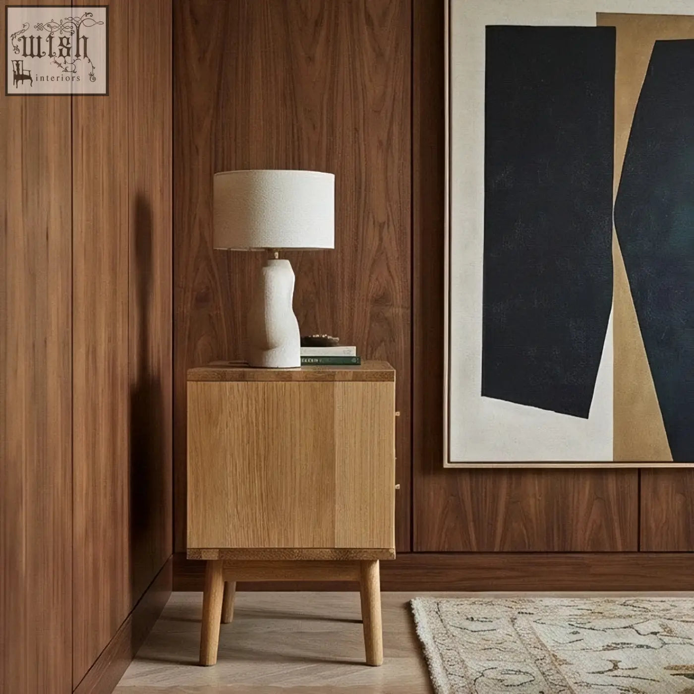A minimalist white ceramic table lamp with sculpted base and linen shade on a solid oak wright oak bedside table
