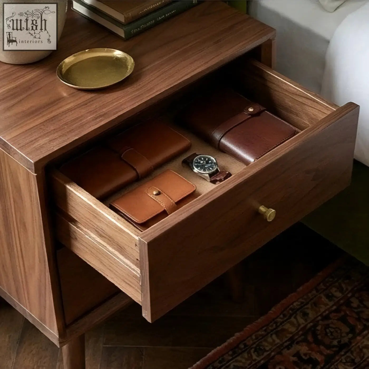 Dark wood solid walnut bedside table with single drawer open showing brown leather wallets and a watch inside