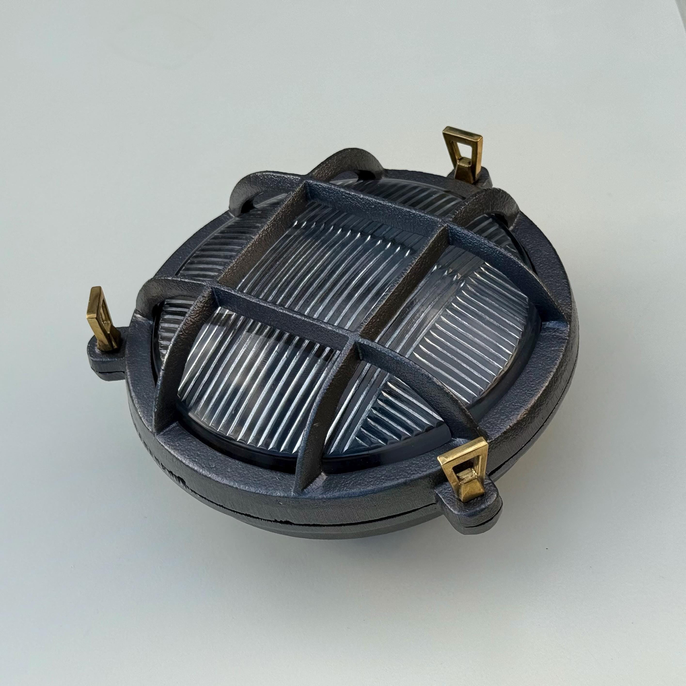 Dark gray cast iron wall light with ribbed glass and brass mounting for nautical bulkhead wall light use